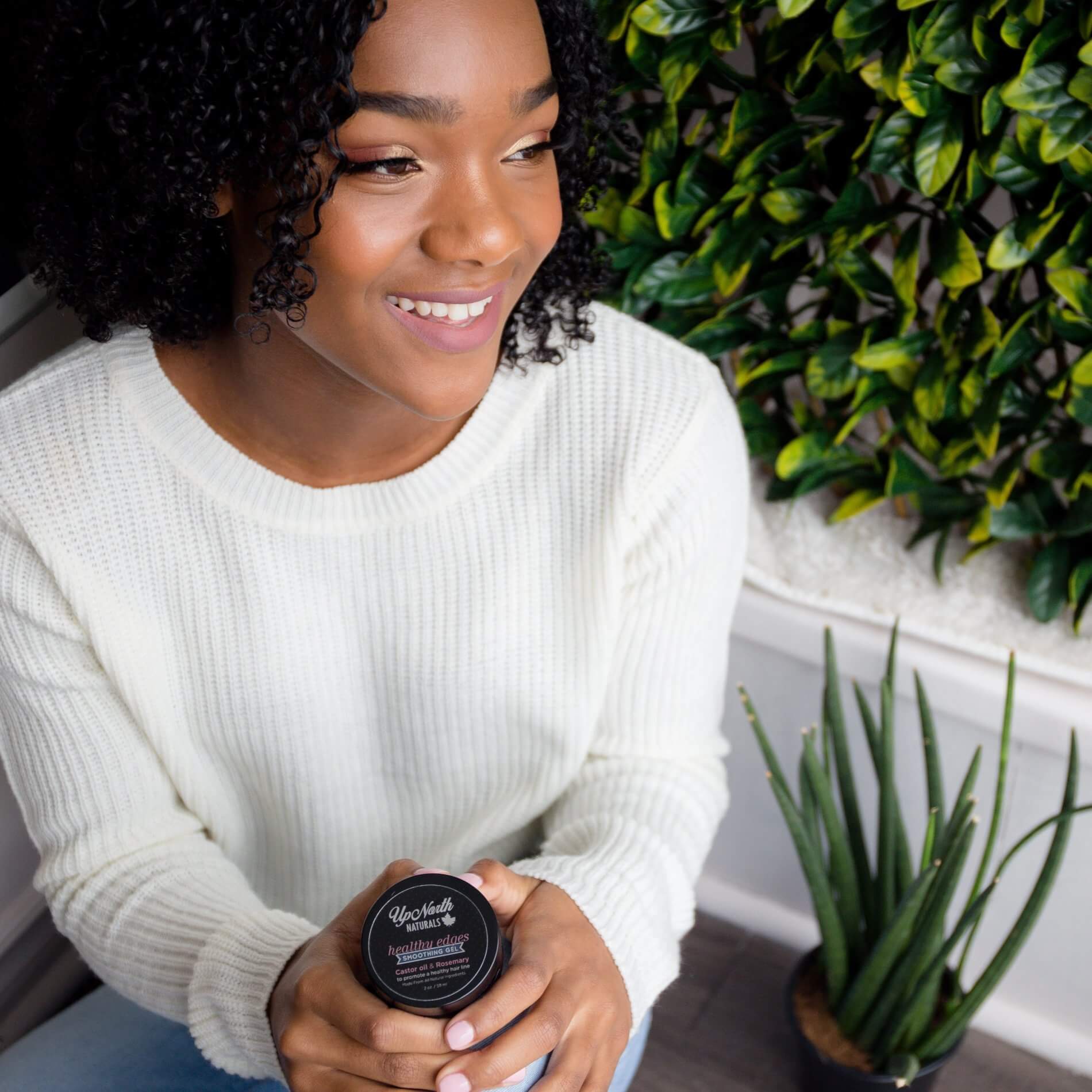 Woman with beautiful naturally curly hair holding healthy edges smoothing gel